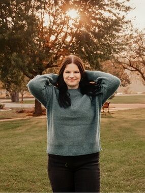 Black slightly ripped flared a skinny jeans pared with dark blue sweater